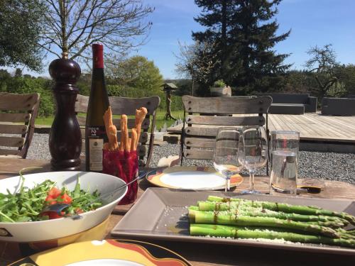 einen Tisch mit einem Teller Gemüse und einer Flasche Wein in der Unterkunft Maison Galerie Art n Pepper in Solwaster