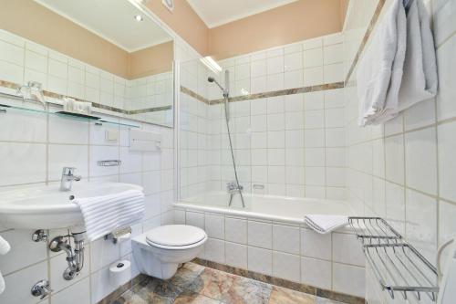 a bathroom with a toilet and a sink and a bath tub at Hotel Windsor in Düsseldorf
