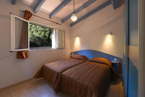 a bedroom with a bed with a blue headboard and a window at Résidence Cantu di Mare in Olmeto