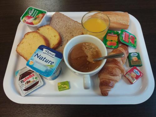 a plate of food with bread and a cup of orange juice at Premiere Classe Roissy CDG - Paris Nord 2 - Parc des Expositions in Roissy-en-France