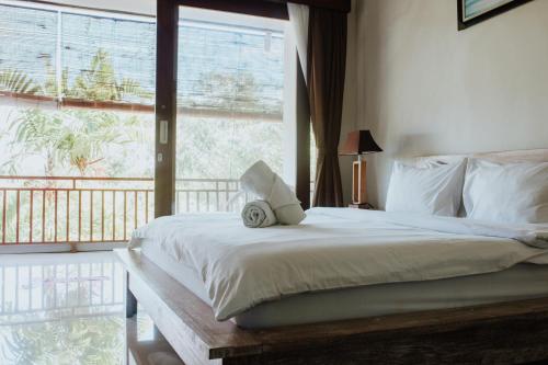 a bedroom with a bed and a large window at Matra Bali Surf Camp in Canggu