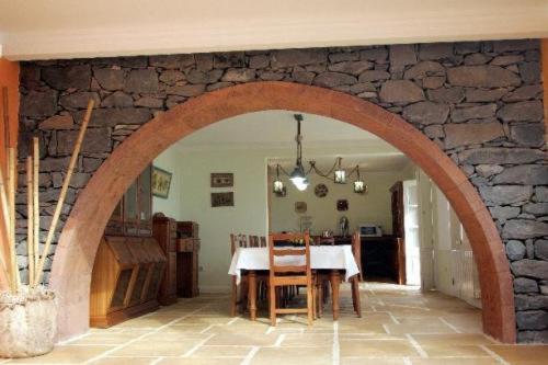 an archway in a room with a table and a stone wall at Colina Da Faja in Fajã da Ovelha
