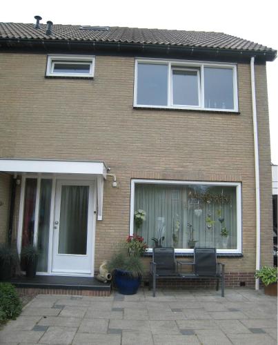 a house with two chairs in front of a window at B&B Marijke in De Koog