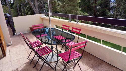 フォン・ロムー・オデイヨ・ヴィアにあるRéidence La Foretのピンクの椅子とガラスのテーブルが備わるバルコニー