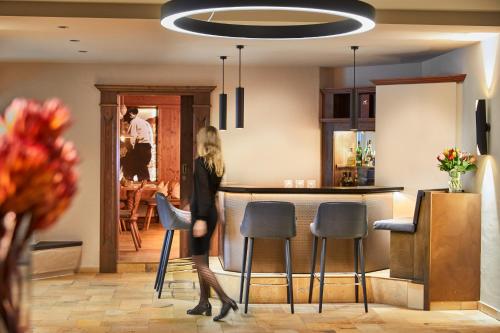 a woman walking past a bar in a kitchen at Alpenrose Kufstein in Kufstein