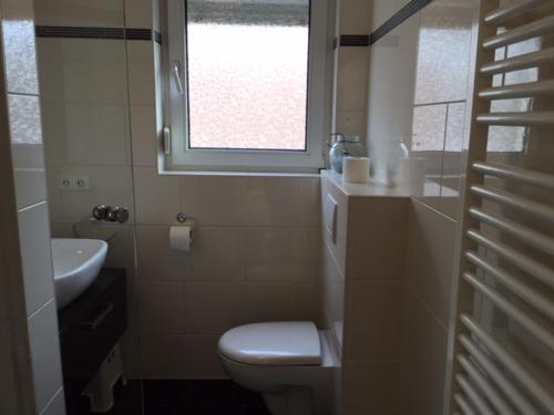 La salle de bains est pourvue de toilettes, d'un lavabo et d'une fenêtre. dans l'établissement FeWo und Zimmer Egert, à Hattenheim