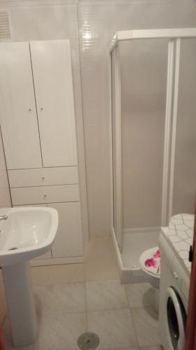 a white bathroom with a sink and a shower at Daria in La Mata