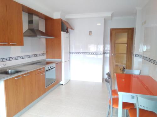 cocina con armarios de madera y encimera roja en H&V Codesal, en Sanxenxo