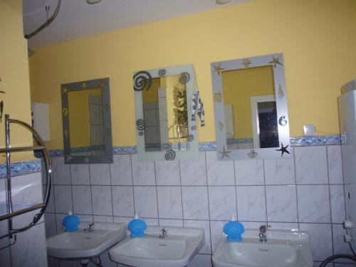 a bathroom with three sinks and two mirrors at Mietwohnwagen in Lonau