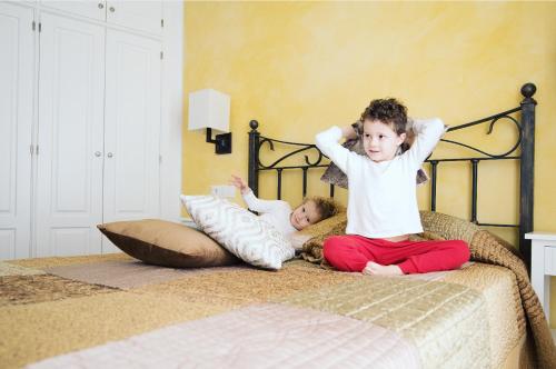 two children are sitting on a bed at La Casa dels Abeuradors in Gandesa