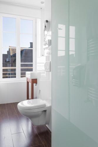 a white bathroom with a toilet and a window at Hotel Mercure Roscoff Bord De Mer in Roscoff