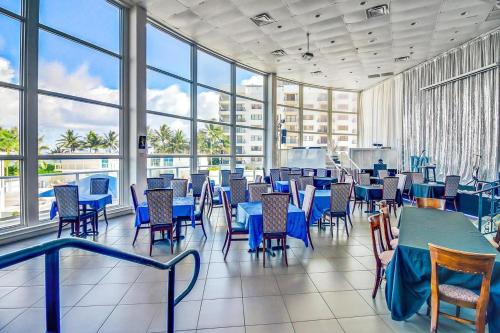 un comedor con mesas y sillas azules y ventanas en Castle Beach Club Apartments, en Miami Beach