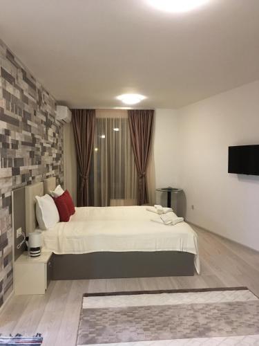 a bedroom with a large white bed and a television at Apartments Park Place in Sandanski