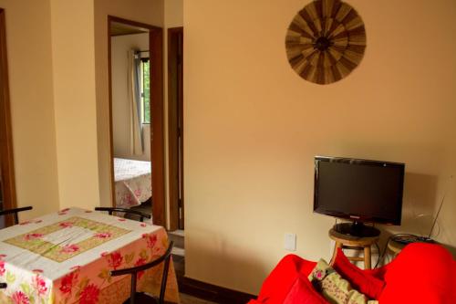 a living room with a tv and a red couch at Casa tranquila perto da Joaquina in Florianópolis