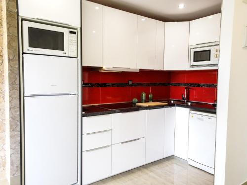 cocina blanca con electrodomésticos blancos y paredes rojas en Apartment Duquesa de España en Torremolinos