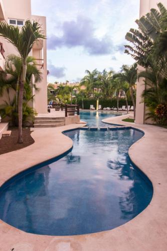 a swimming pool in a resort with palm trees at Coral Maya Stay Suites in Puerto Aventuras