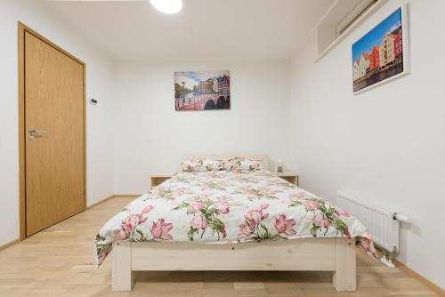 a white bedroom with a bed with a floral bedspread at Telliskivi apartment 16 in Tallinn