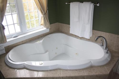 a large white tub in a bathroom with a window at Pathsaala Inn & Restaurant in Perth