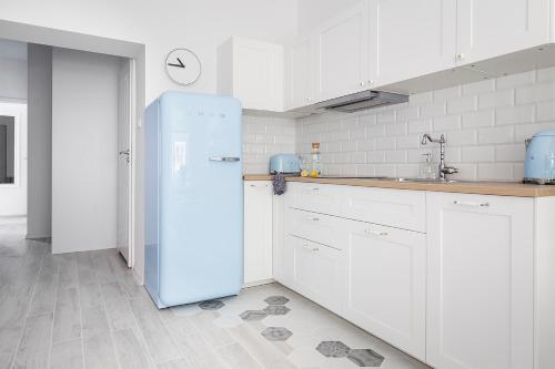 グダニスクにあるApartament Błękitny | Chill and the City Apartmentsの- 青い冷蔵庫、白いキャビネット付きのキッチン