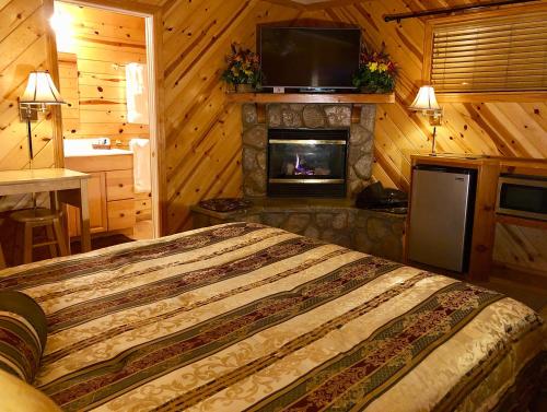 a bedroom with a bed with a fireplace and a television at Giant Oaks Lodge in Running Springs
