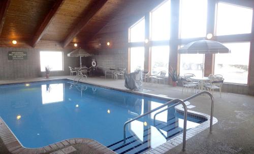 a large swimming pool in a building with tables and chairs at AmericInn by Wyndham Marshall in Marshall