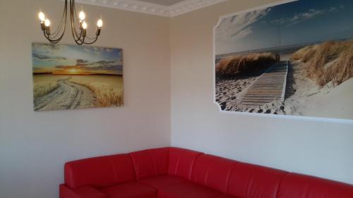 a red couch in a room with two pictures on the wall at Landhaus von Felde in Esens