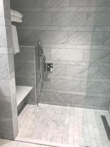 a shower in a bathroom with a stone wall at The Preston House and Hotel in Riverhead