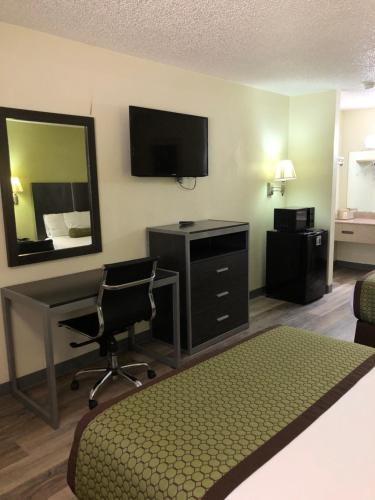 a hotel room with a bed and a desk and a television at Southern Inn Minden in Minden