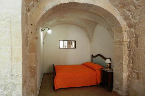 シクリにあるLe volte di Giudittaのアーチの上にオレンジのベッドが備わるベッドルーム1室