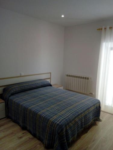 ein Schlafzimmer mit einem Bett mit einer blau gestreiften Decke in der Unterkunft Alojamiento Samumari in Ciudad-Rodrigo