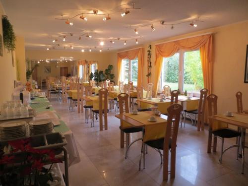 a dining room with tables and chairs and windows at Hotel Merkur Garni in Sarstedt