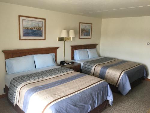 una habitación de hotel con 2 camas y una lámpara en Coho Motel, en Kewaunee