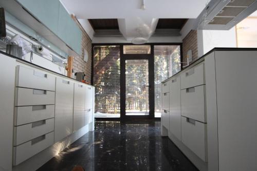 a kitchen with white cabinets and a large window at Champêtre Park View Apartments in Rīga