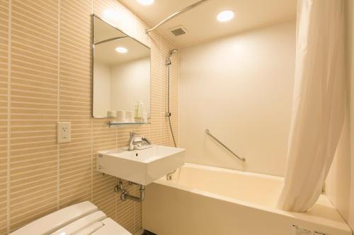 a bathroom with a sink and a toilet and a tub at Nishitetsu Inn Kurosaki in Kitakyushu