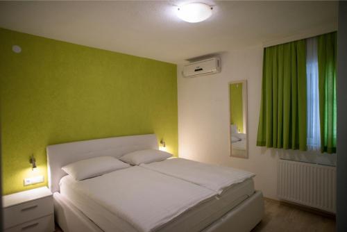 a bedroom with a white bed with a green wall at Villa Lika in Plitvička Jezera