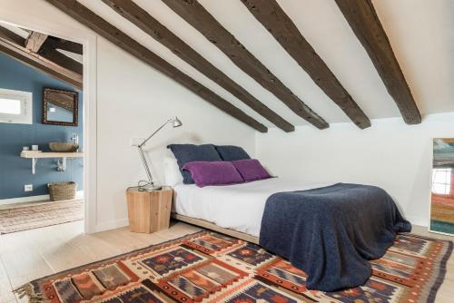 マドリードにあるBNBHolder Awesome Duplex Attic SOLのベッドルーム1室(紫色の枕とラグ付)