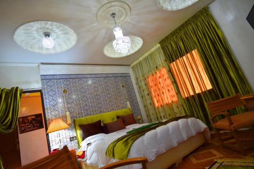 a bedroom with a bed with green curtains and two lights at Maison d'hôtes La Ferme AZIZA in Fès