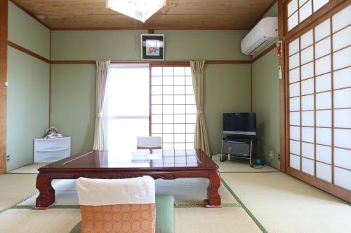 sala de estar con mesa y ventana en Shirasakiso, en Yura