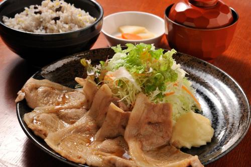 a plate of food with meat and rice on a table at Matsumoto Tourist Hotel in Matsumoto