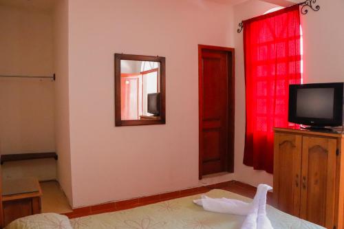 a room with a mirror and a tv on the wall at MESÓN DE LOS ÁNGELES in Comitán de Domínguez