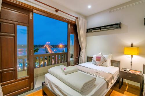 a bedroom with a balcony with a bed and a window at B'Lan Riverside Villa in Hoi An
