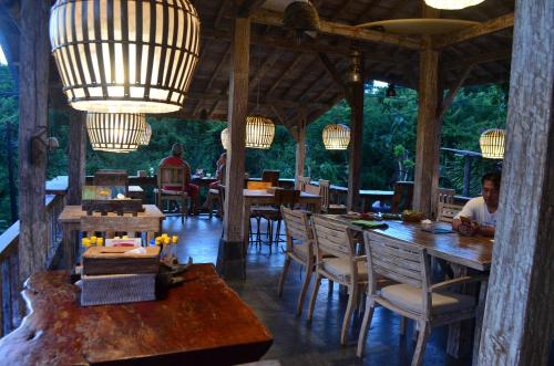 a restaurant with wooden tables and chairs and chandeliers at Padang Padang Breeze in Uluwatu