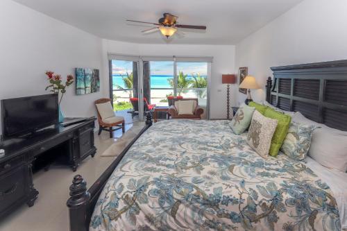 1 dormitorio con 1 cama grande, TV y océano en Condo Corazon - True Beachfront Golf Course Condo - At Mareazul, en Playa del Carmen