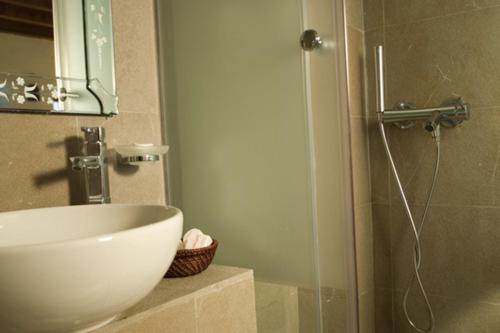 uma casa de banho com um lavatório e um chuveiro com um espelho. em Domus Studios in Ilha de Rhodes