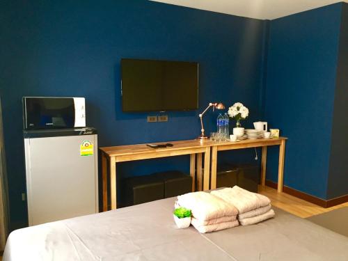 a room with a desk with a television and a table with towels at My Home N1 - BTS Ratchathewi in Bangkok