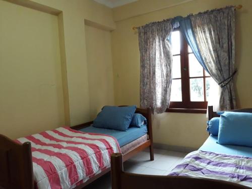 a bedroom with two beds and a window at Lippo Carita Beach Utara Condo Noah in Carita