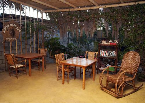 a patio with tables and chairs and a book shelf at AquamarInn in Máncora