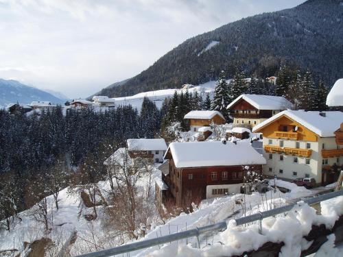 un pueblo cubierto de nieve con edificios y árboles en Pension Bichlgeiger, en Anras