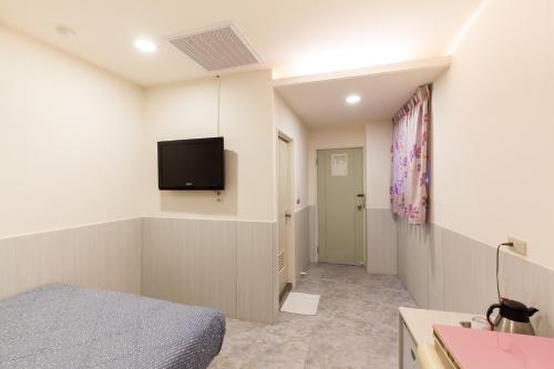 a bedroom with a bed and a tv on the wall at Ruei Gung Business Hotel Kaohsiung in Kaohsiung