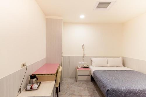 a small room with two beds and a table at Ruei Gung Business Hotel Kaohsiung in Kaohsiung